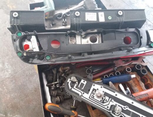 Fanale posteriore Fiat smontato presso l'autofficina F.LLI BASSO SNC a Imperia, con attrezzi e minuteria per la riparazione.