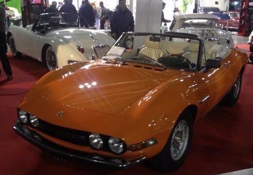 Auto d'epoca Menegatto Roberto: Elegante Fiat Dino Spider arancione in esposizione, icona del design automobilistico italiano, presso l'autofficina multimarca.