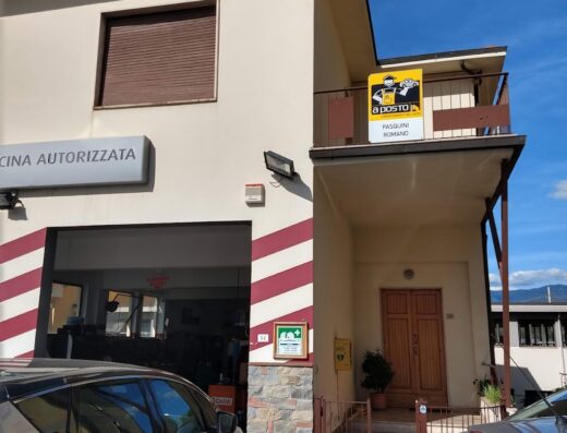 Esterno dell'Autofficina Pasquini Romano, con insegna "Officina Autorizzata" e veicoli parcheggiati. Servizi di riparazione auto e manutenzione moto.