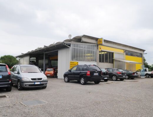 Autofficina Pizzuto snc: vista esterna dell'officina con diverse auto parcheggiate, servizi di riparazione e manutenzione per auto e moto.