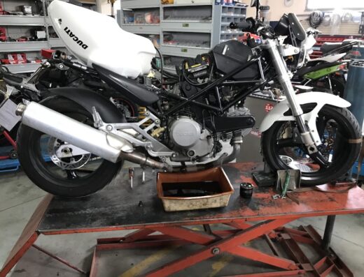 Autofficina Trasimeno: Ducati Monster bianca in riparazione sul ponte sollevatore. Cambio olio e manutenzione moto nel reparto specializzato.