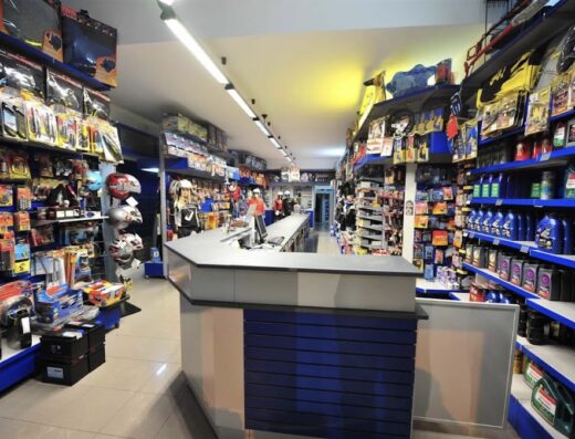 Interno del negozio Autoforniture Bellino, con scaffali pieni di accessori e ricambi per moto, caschi e lubrificanti.