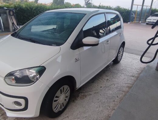 Autolavaggio: Volkswagen Up bianca in un'area self-service per la pulizia auto. Dettaglio della carrozzeria e delle attrezzature per il lavaggio.