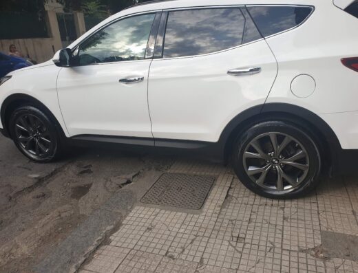 Dettaglio di un SUV bianco pulito in un autolavaggio, con pneumatici neri lucidi e riflessi di luce sulla carrozzeria.