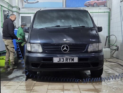 Autolavaggio: Un furgone Mercedes nero viene lavato all'interno di un autolavaggio, con due persone che si prendono cura della pulizia.