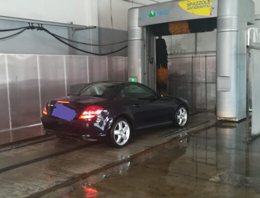 Auto nera in un autolavaggio 5 Minuti con spazzole antigraffio, servizio rapido e efficace per la cura dell'auto e della carrozzeria.