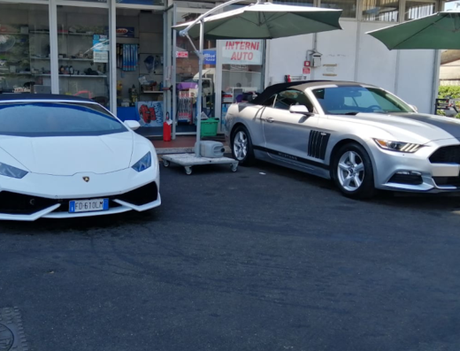 Autolavaggio a mano: Lamborghini bianca e Ford Mustang argento cabriolet parcheggiate di fronte all'autolavaggio, in attesa del servizio di pulizia auto.