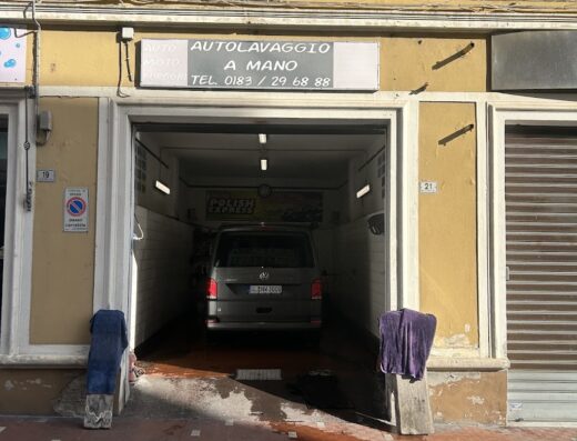 Autolavaggio a mano di Roattino Ugo: Furgone grigio in autolavaggio con insegna "Autolavaggio a mano" e numero di telefono.