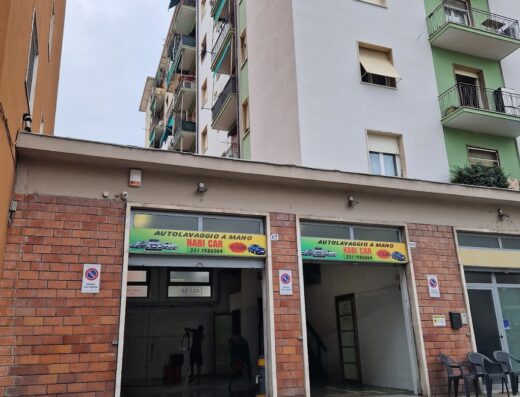 Autolavaggio a mano "Habi Car", servizio di lavaggio auto a mano con insegna ben visibile e personale al lavoro, situato in contesto urbano.