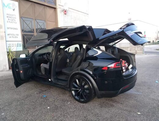 Autolavaggio a mano I faraoni: Tesla Model X nera con portiere ad ala di gabbiano aperte durante il lavaggio auto professionale.