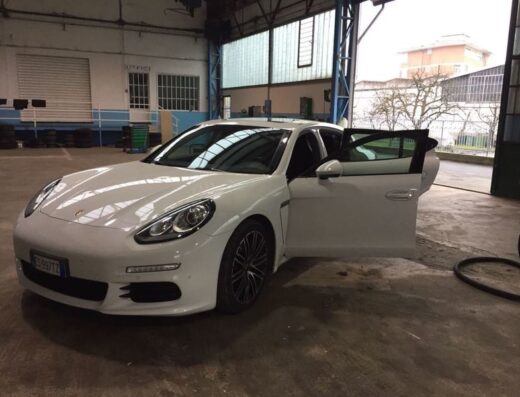 Autolavaggio a Mano San Mauro: Una Porsche bianca con una portiera aperta all'interno di un'officina per l'autolavaggio.