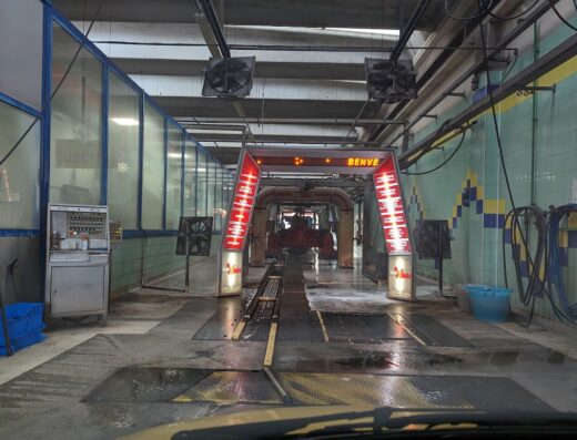 Interno di un autolavaggio "Car Wash" con rulli e attrezzature per la pulizia dei veicoli, illuminato e pronto per il servizio.