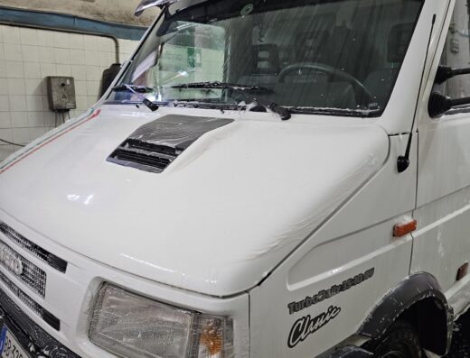Autolavaggio Car Wash di Noto Massimo: un furgone bianco Iveco Daily Classic Turbo in fase di lavaggio, coperto di schiuma, presso l'autolavaggio.