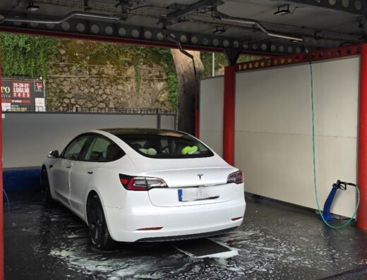 Autolavaggio Quick Quack: Tesla Model 3 bianca in servizio di lavaggio auto a Viale Fieschi. Dettaglio schiuma e accessori.