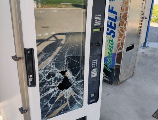 Distributore automatico 'Panno Self' vandalizzato con vetro rotto presso l'autolavaggio del CC La Fattoria, servizio di pulizia moto danneggiato.