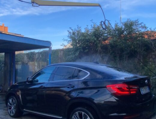 Autolavaggio Cleancar: SUV nero in fase di lavaggio esterno, dettaglio sulla carrozzeria e sui cerchi in lega.