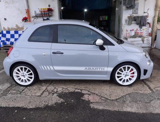 Autolavaggio del centro: Fiat Abarth grigia con cerchi bianchi appena lavata, dettaglio della fiancata con scritta Abarth.
