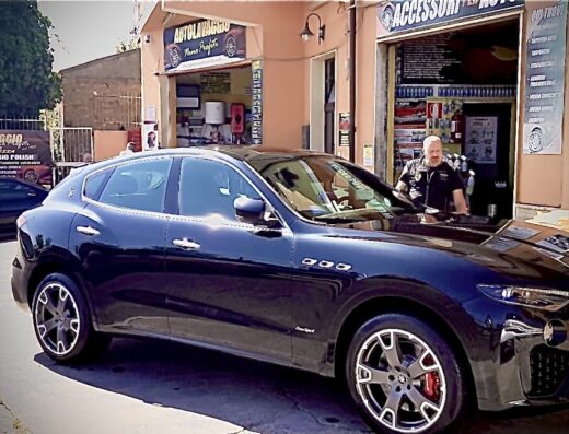 Autolavaggio di Nino Profiti: Maserati Levante nera in primo piano durante un servizio di autolavaggio. Un uomo in abbigliamento da lavoro è visibile sullo sfondo.
