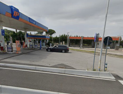 Stazione di servizio IP con autolavaggio Orlandi Marco, moto parcheggiata, auto in sosta e area di lavaggio auto.