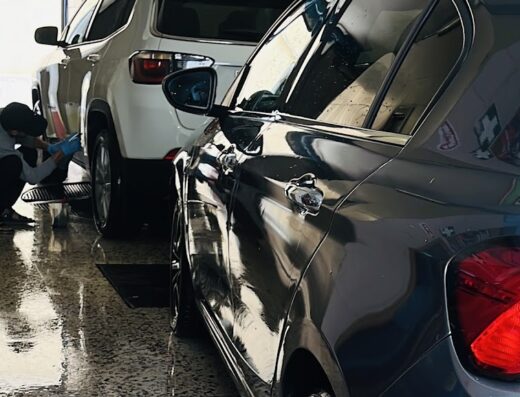 Autolavaggio di Paolo Di Dio: Un addetto lava accuratamente un'auto bianca e una grigia, servizio professionale per la cura del veicolo.