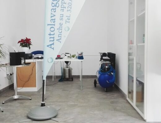 Interno dell'autolavaggio di Stefanini Marco con insegna pubblicitaria, compressore, scrivania e accessori per moto. Servizi di lavaggio moto su appuntamento.