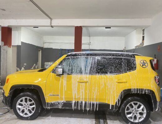 Autolavaggio DODO: Jeep Renegade gialla sottoposta a lavaggio auto professionale con schiuma, dettaglio della carrozzeria e degli interni.