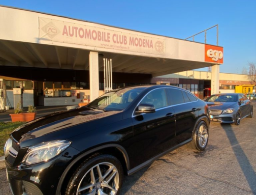 Autolavaggio e rifornimento carburante da Billy: un'elegante Mercedes-Benz nera parcheggiata di fronte all'Automobile Club Modena e alla stazione di servizio Ego. Servizi di autolavaggio e carburanti per auto e moto a Modena.