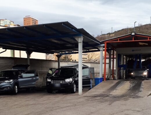 Autolavaggio F.lli Atena: Immagine di un autolavaggio con auto in fase di lavaggio e altre parcheggiate sotto una tettoia.