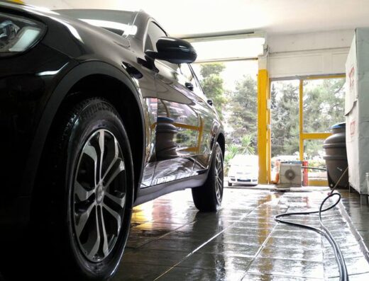 Autovettura nera di lusso presso Autolavaggio Giglio, dettaglio cerchioni e carrozzeria lucida dopo il servizio di lavaggio.