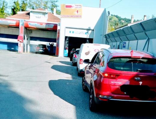 Autolavaggio Gioia Wash: fila di auto in attesa di lavaggio, con una Kia Sportage rossa in primo piano. Servizio di pulizia auto professionale.
