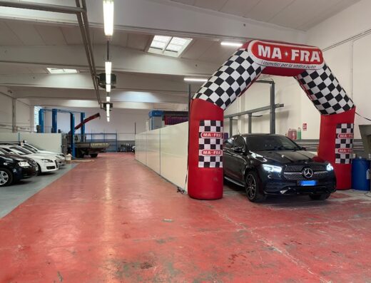 Autolavaggio GP Car: Una Mercedes-Benz nera lucida sotto un arco gonfiabile Ma-Fra in un'officina di autolavaggio, pronta per un servizio di pulizia auto professionale.