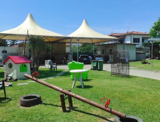 Area esterna dell'Autolavaggio L'Obelisco di Marcuccetti Sara con giochi per bambini, inclusa un'altalena a bilico con pneumatici, tavolino e sedie da giardino.