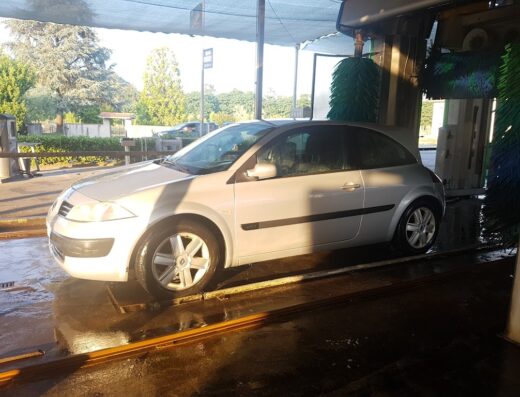 Autolavaggio Luca e Marco: un'auto grigia in un impianto di autolavaggio con spazzole rotanti per la pulizia.