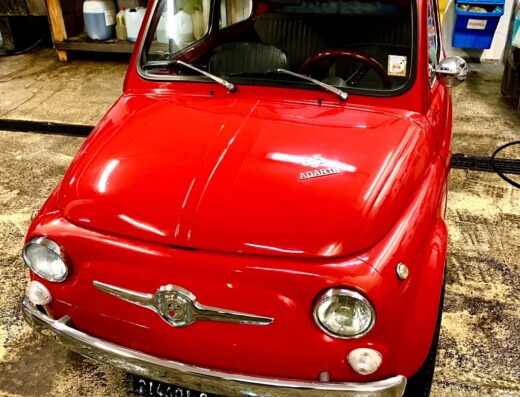 Autolavaggio M.2: Dettaglio di una Fiat 500 Abarth rossa classica durante il servizio di autolavaggio, cura e pulizia auto.