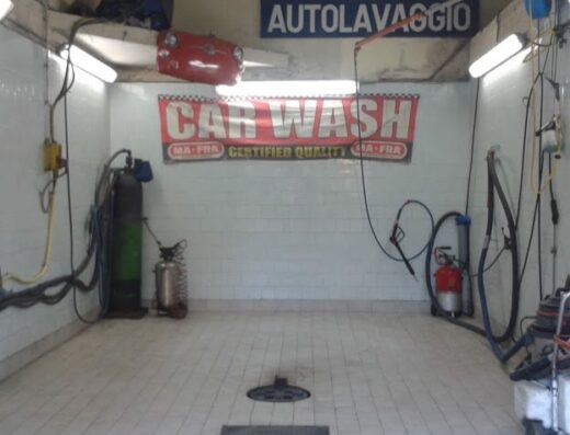 Interno dell'autolavaggio manuale Francesco, con attrezzature per la pulizia moto e auto, inclusi compressori, idropulitrici e insegna "CAR WASH".
