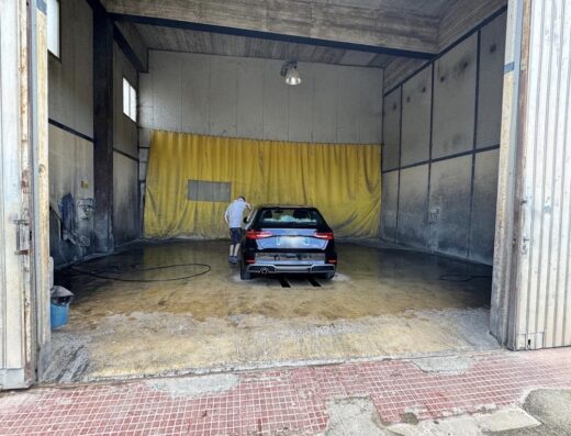 Autolavaggio Mazzara Antonino: Uomo che lava una macchina nera all'interno dell'autolavaggio, servizio professionale di pulizia auto a Mazzara.