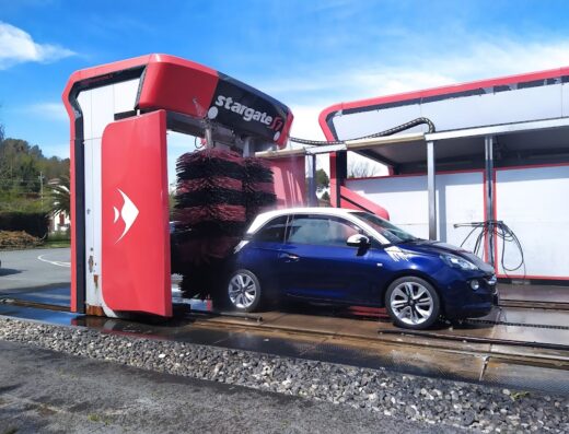 Autolavaggio Oilone: Un'auto blu viene pulita in un impianto di autolavaggio moderno con spazzole rotanti e sistema Stargate.