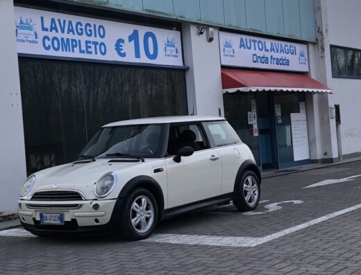 Autolavaggio Onda Fredda: Mini Cooper bianca parcheggiata di fronte all'autolavaggio con cartello "Lavaggio Completo €10".