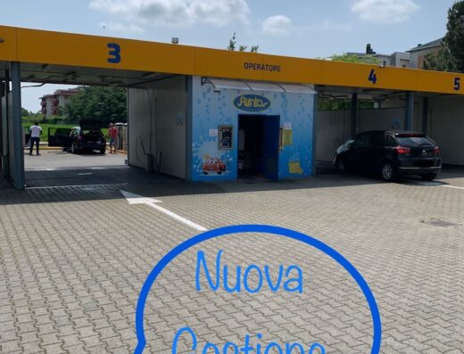 Autolavaggio PUNTO CARWASH: vista esterna della stazione di lavaggio auto con box numerati e cabina operatore, servizio di pulizia auto self-service e professionale.