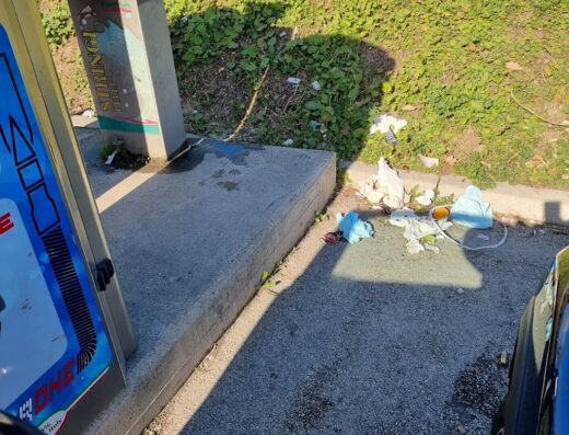 Dettaglio di un'area di lavaggio self-service per moto con accessori, evidenziando la presenza di rifiuti e sporcizia.