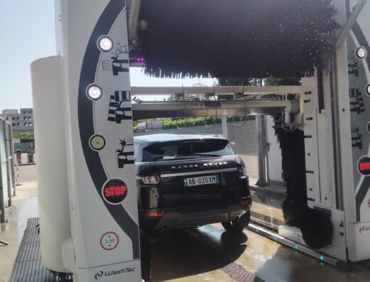 Autolavaggio self-service MAC: un'auto Range Rover nera in un impianto di lavaggio automatico WashTec, con spazzole rotanti per la pulizia.