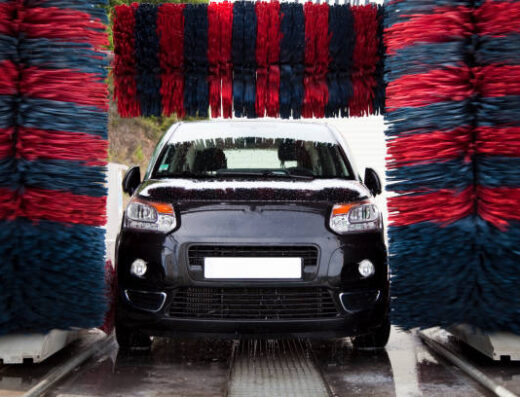 Autolavaggio automatico: auto nera in fase di lavaggio con spazzole rotanti blu e rosse, servizio di pulizia auto all'Antico Passaggio.