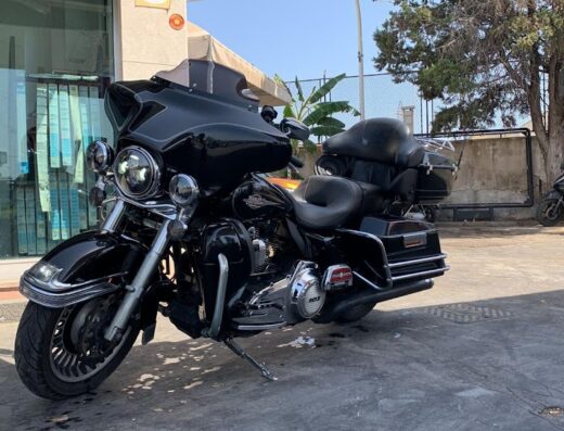 Autolavaggio Sun Luxury Car Wash: motocicletta Harley-Davidson nera parcheggiata, accessoriata con bauletto e parabrezza, in attesa di lavaggio.