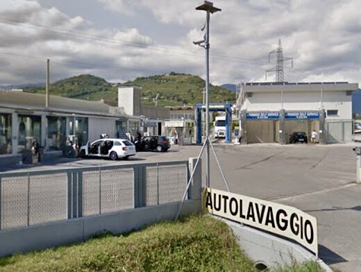 Autolavaggio System Wash Soligo: vista esterna dell'autolavaggio con box self service, pista di lavaggio auto e cartello stradale.