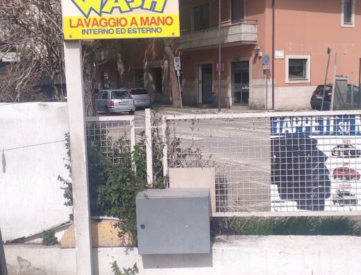 Insegna dell'autolavaggio Tommy che offre lavaggio a mano interno ed esterno per auto, con illustrazione di un'auto lavata con spugna.