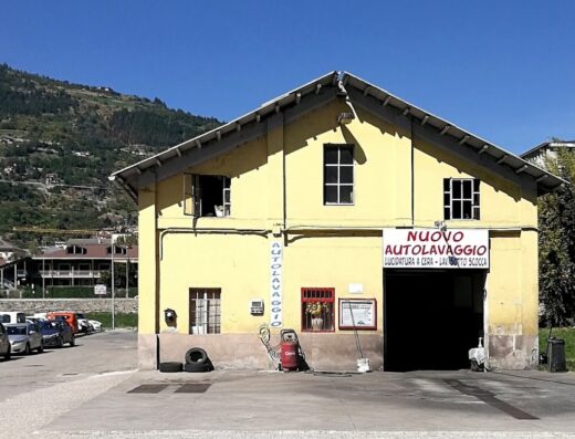 Autolavaggio Turbo Wash: Facciata esterna di un autolavaggio per moto e auto, con insegna "Nuovo Autolavaggio" e attrezzature per la pulizia.