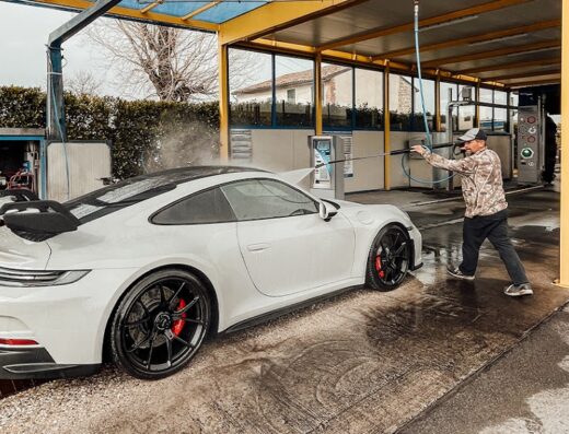 Autolavaggio Wow Detailing: Uomo che lava una Porsche bianca con idropulitrice ad alta pressione, servizio di pulizia auto professionale.
