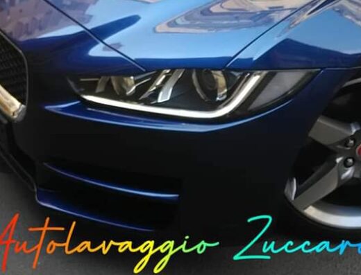 Primo piano della parte anteriore di un'auto blu presso Autolavaggio Zuccaro, con dettagli del faro e della ruota.