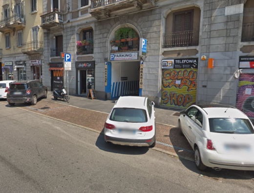 Autolavaggio Loreto: Strada cittadina con parcheggio, moto parcheggiata sul marciapiede e auto in sosta, servizi per veicoli in zona.