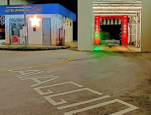 Autolavaggio ZM: modern car wash service station at night, featuring bright lighting and a sign for "LAVAGGIO" on the pavement, perfect for motorcycle and car cleaning.
